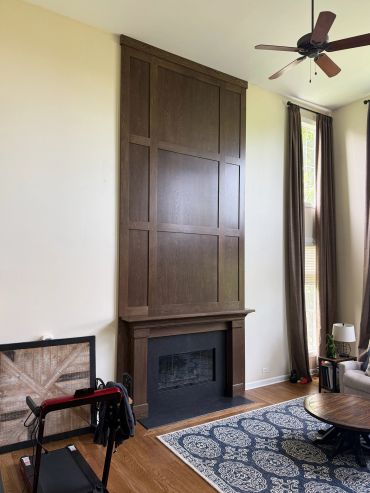 Tall wooden fireplace with modern decor in a bright living room.