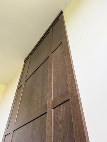 Tall wooden paneling reaching up to the ceiling on a light-colored wall.