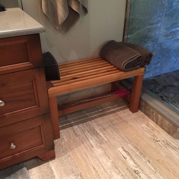 Wooden bench with a rolled towel in a bathroom corner.