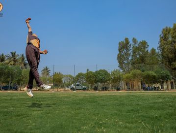 Person jumping and catching a ball in a park on a sunny day.
