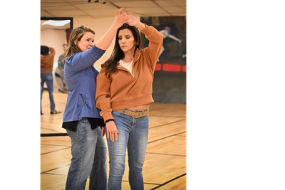 Two women dancing in a gymnasium.