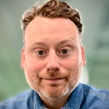 Close-up portrait of a man with a beard wearing a blue shirt.
