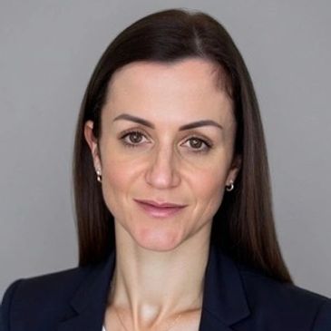 Professional woman with long dark hair wearing a navy blazer.