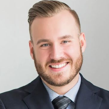 Smiling man in a suit and tie with a neatly groomed beard.