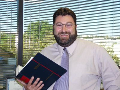 Man smiling in office holding a book.