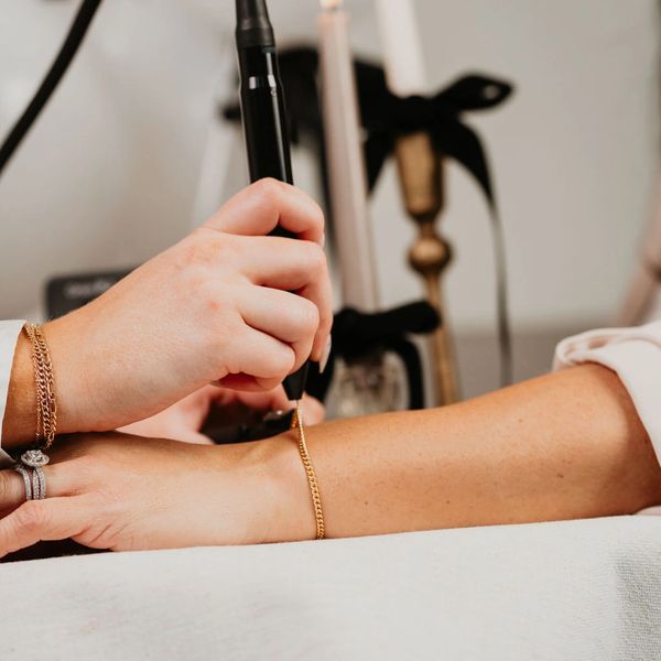 Person using a handheld device on another person's wrist indoors.