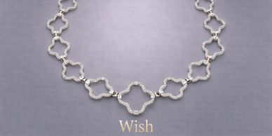 Elegant diamond necklace with clover-like links on a soft gray background.