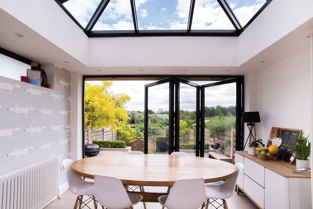 Inside of a house with white painted walls and black aluminium windows, bifold doors and lantern