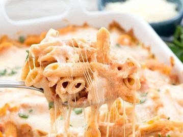 Cheesy baked penne pasta being served, with melted cheese stretching.