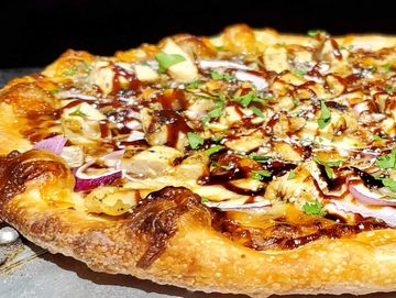 Close-up of a delicious BBQ chicken pizza with fresh herbs.