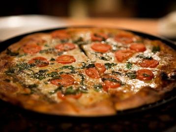 A delicious pizza with tomato and herbs sliced on a plate.