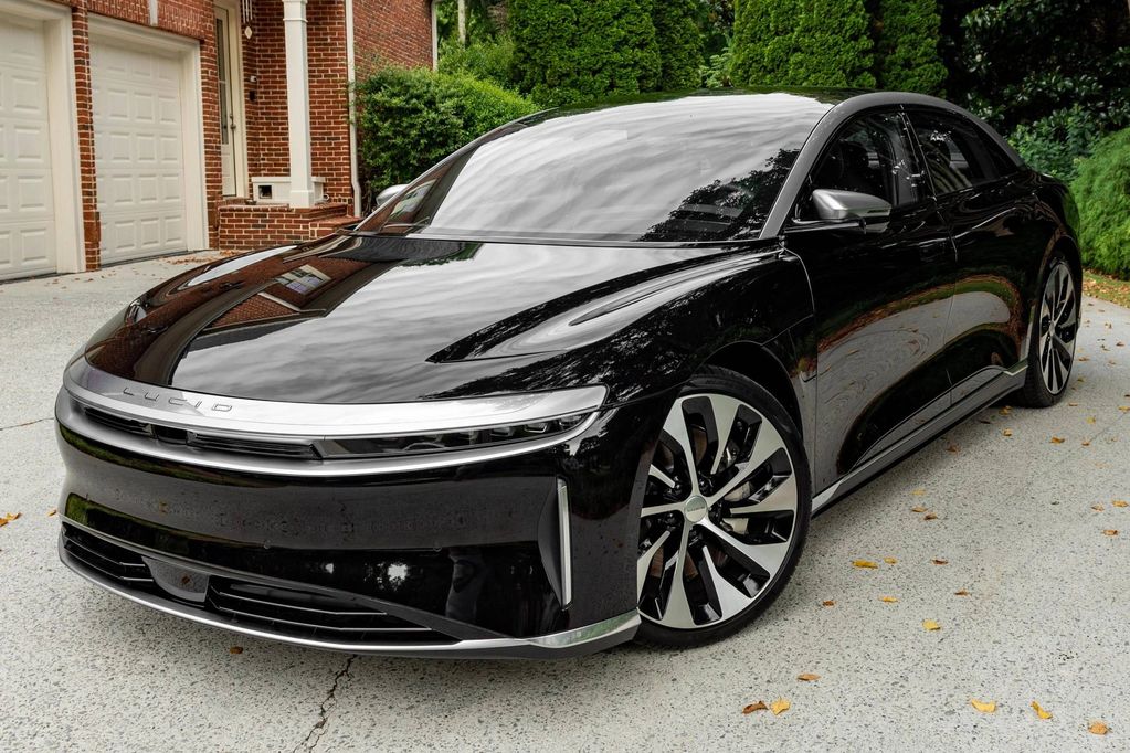Sleek black Lucid electric car parked on driveway with reflective surface.