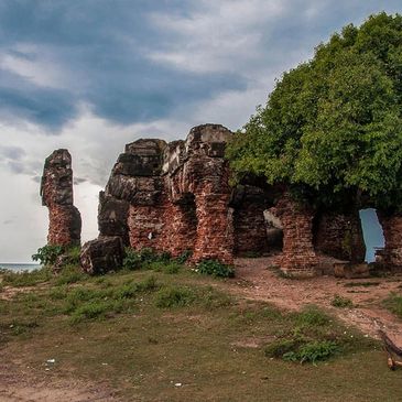 Ancient red brick ruins with arches under a cloudy sky.