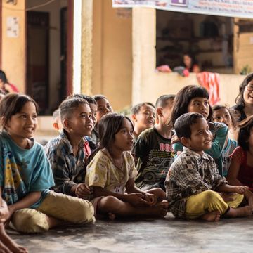 Happy children in a developing economy listening to a teacher. photo credit: Yannis H on Unsplash