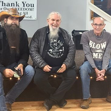 Three men sitting indoors, smiling and relaxed.