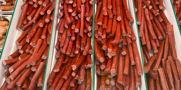 Rows of different types of sausages on display in trays.
