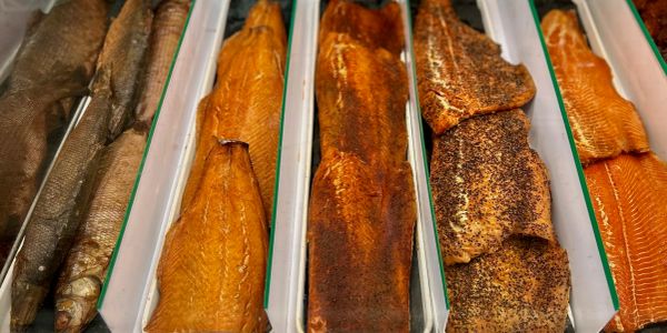 Various smoked fish fillets displayed in trays at a market.