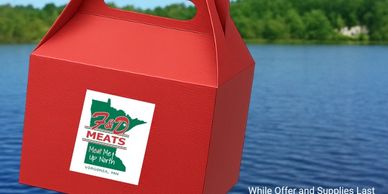 Red takeout box from 3rd St Meats with a green outdoor background.