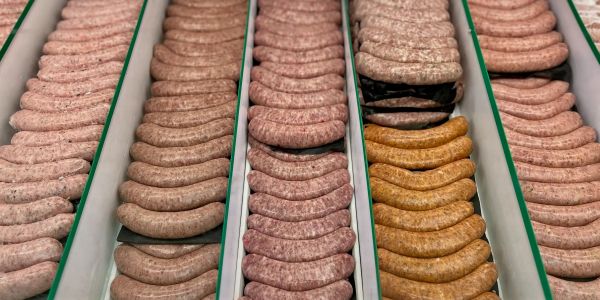 Rows of various types of sausages neatly arranged in trays.