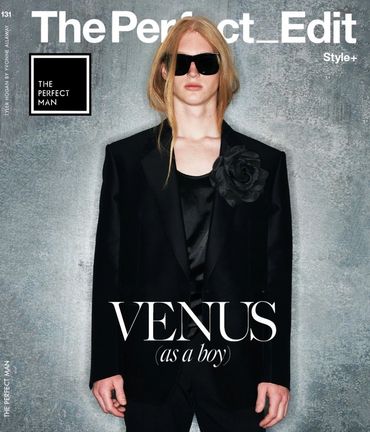Fashion magazine cover featuring a model in black suit and sunglasses.