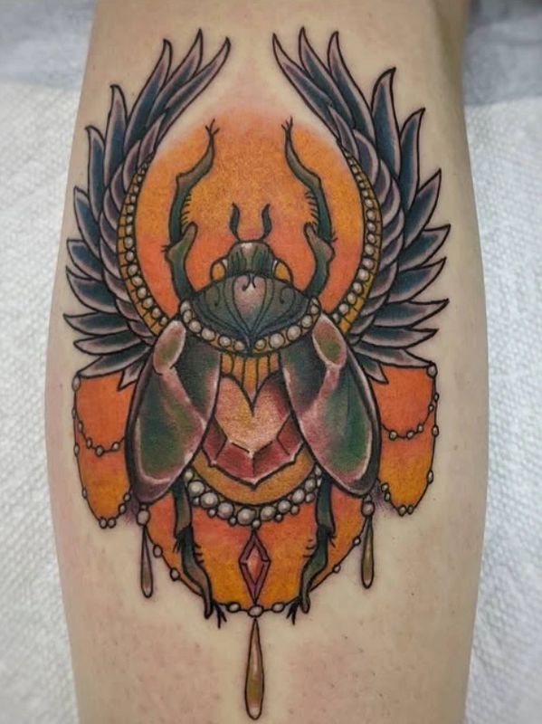 Colorful scarab beetle tattoo with wings and ornamental details.