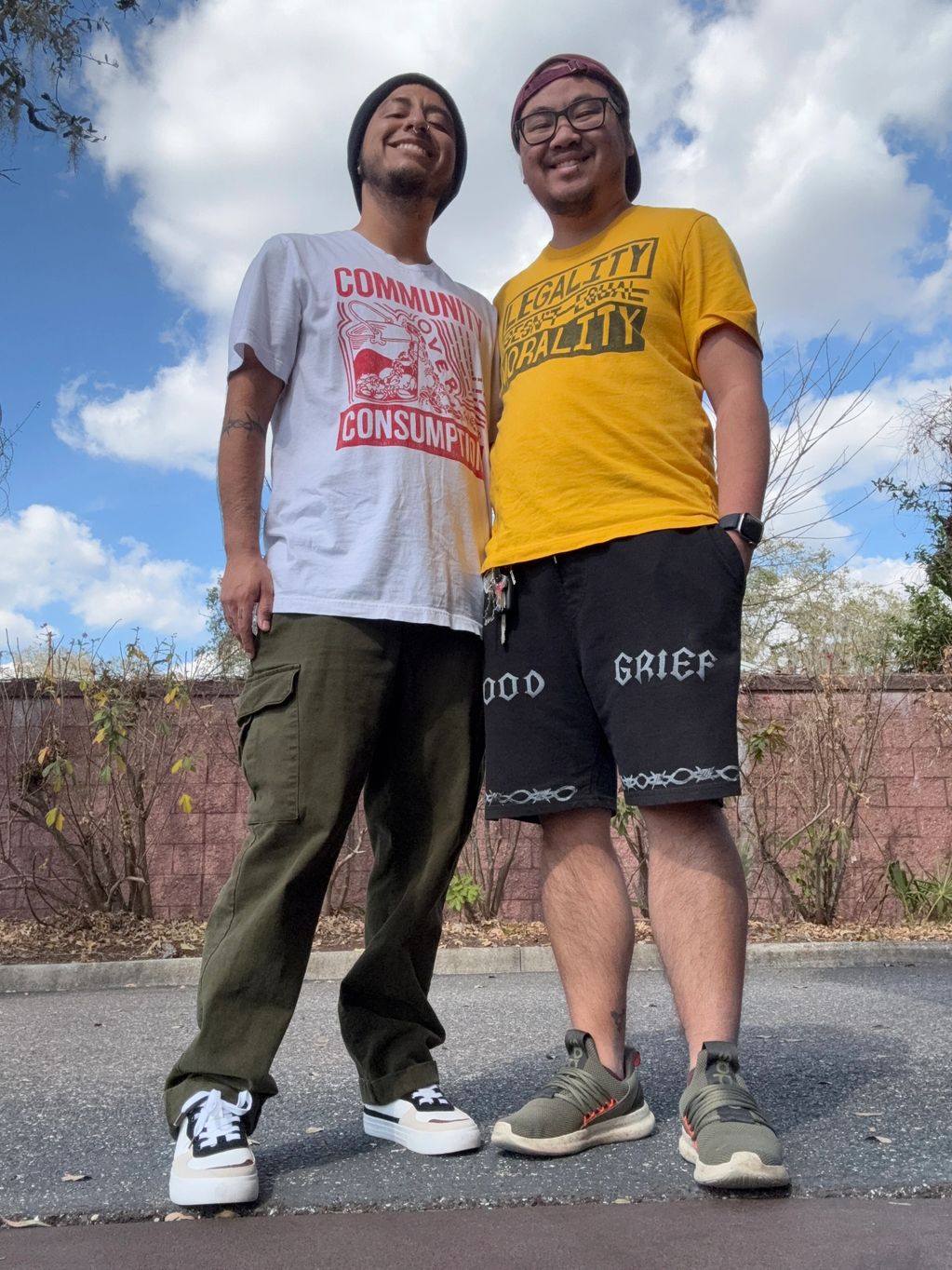 Two masculine - presenting people of color stand side by side, both wearing Uppercutt merch, smiling