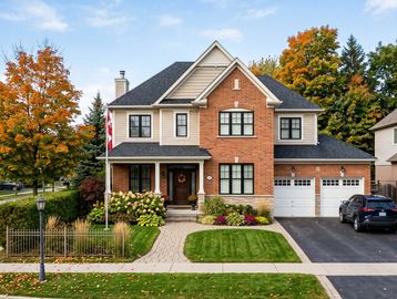 Two-story suburban house with brick and beige siding, surrounded by autumn trees.