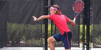 Young tennis player preparing to hit a backhand shot on the court.