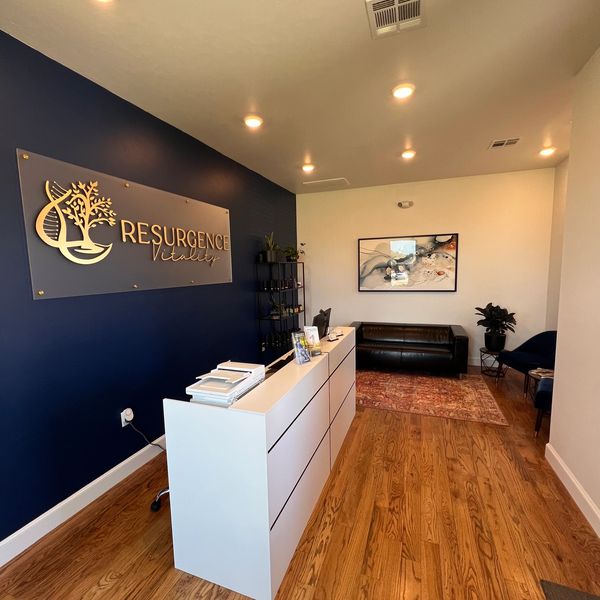 Modern reception area with a white desk and blue accent wall at Resurgence Vitality in Edmond, Oklahoma.