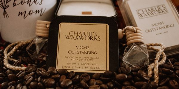 Coffee scented candle, wax melt, and car fresheners in a bed of coffee beans with dedication to Moms