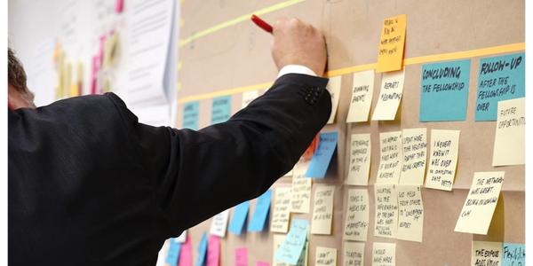 Man writing on a wall of sticky notes.