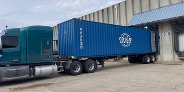 A blue COSCO container on a semi-truck at a loading dock.