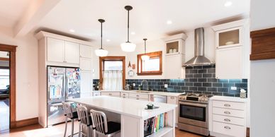 Large kitchen with white cabinetry, dark blue subway tile backsplash and island with seating.