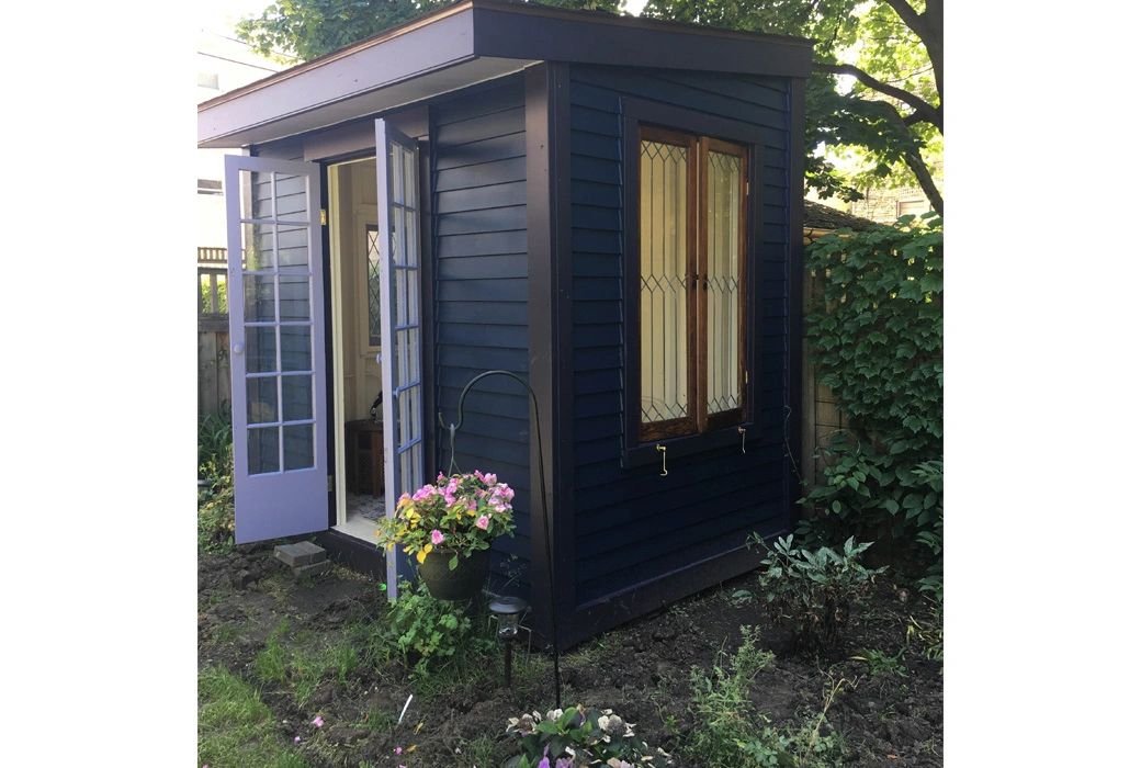 Backyard she shed painted shades of purple with vintage stained glass windows.