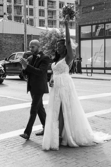 Bride and groom celebrating on city street after wedding ceremony.