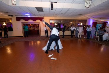 Groom dipping bride on the dance floor with guests watching.