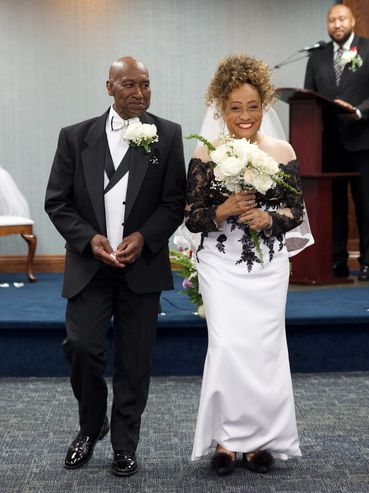 Happy couple in wedding attire walking down the aisle.