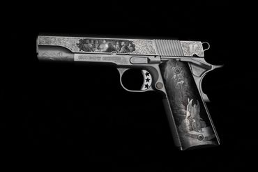 Intricately engraved silver handgun with detailed artwork on a black background.