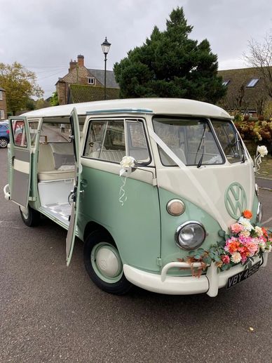 A vintage Volkswagen van decorated with flowers and ribbons.