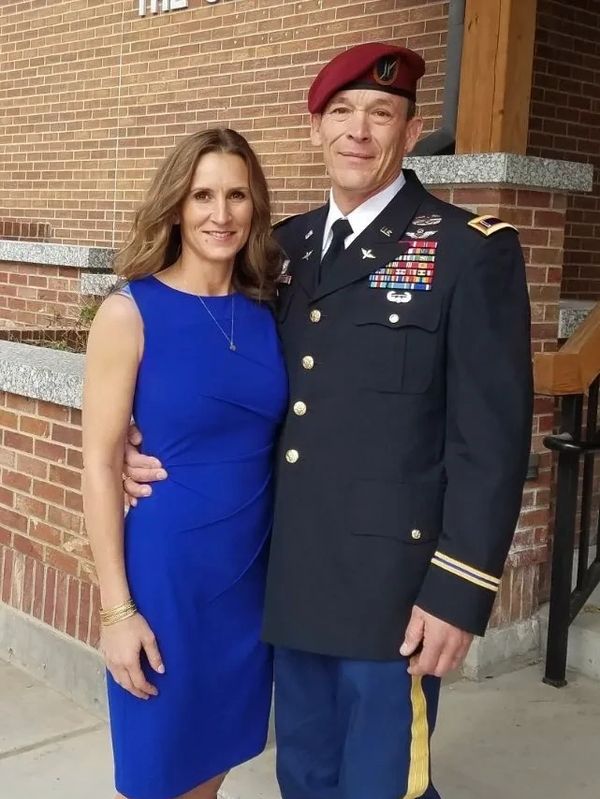 A couple posing, man in military uniform, woman in blue dress.