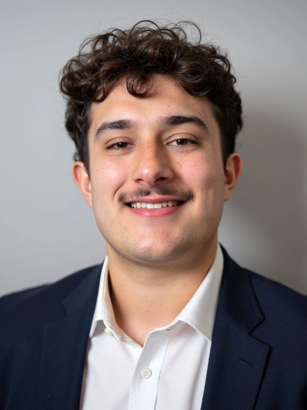 Portrait of a young man with curly hair and a mustache.