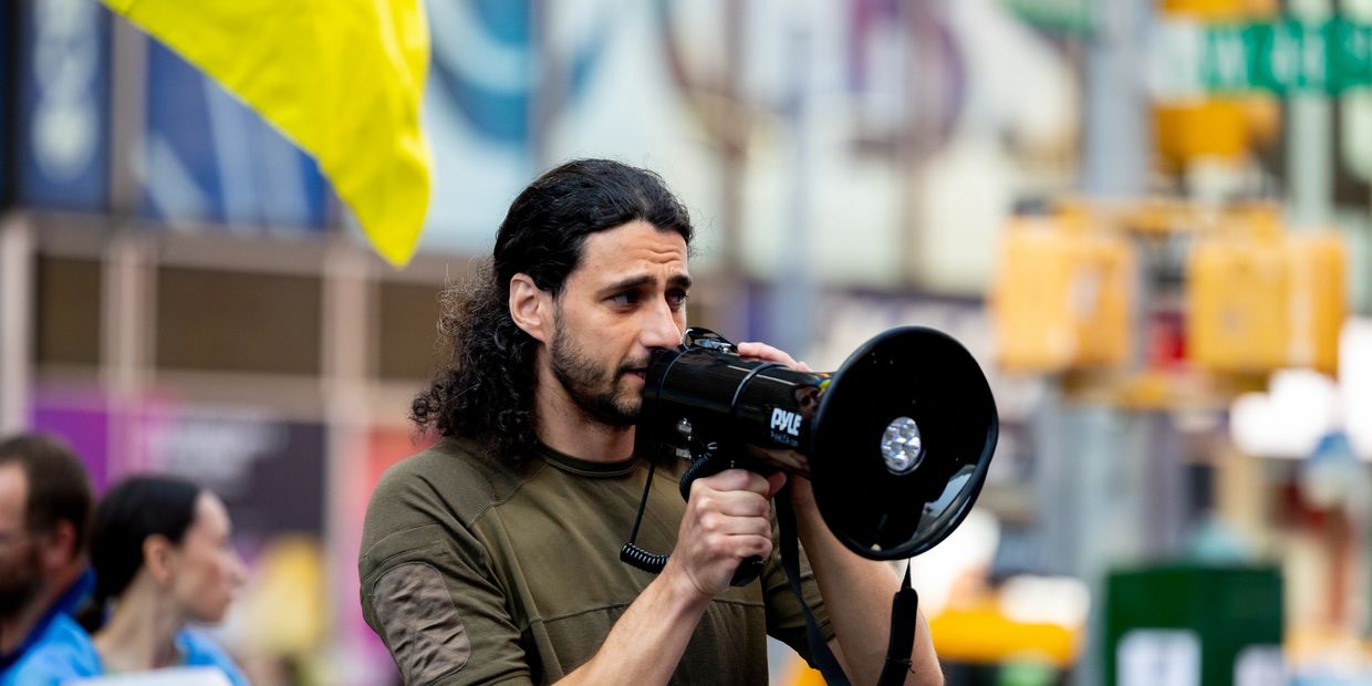 Vsevolod Myrnyi speaking into a megaphone at a protest.