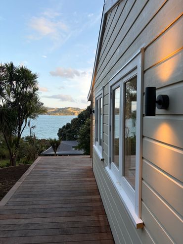 Wooden deck beside a house with ocean view and palm trees.