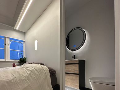 Modern bedroom and bathroom with sleek design and ambient lighting.