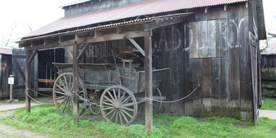 Old wooden wagon displayed outside a rustic barn.