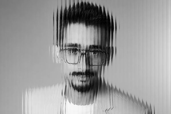 A man's distorted face through textured glass.