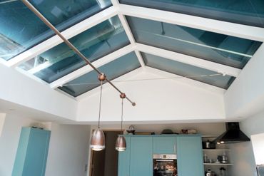 Modern kitchen with large glass skylight and pendant lights.