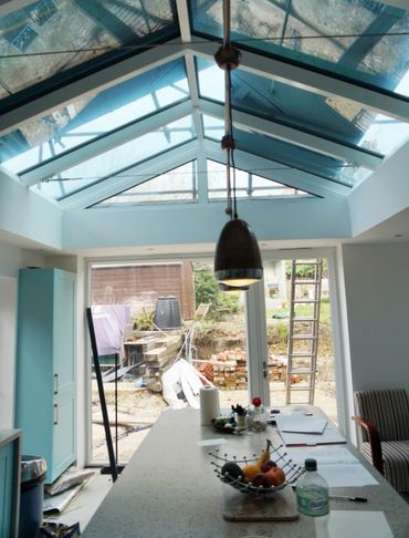 Modern kitchen with glass ceiling and outdoor view under construction.
