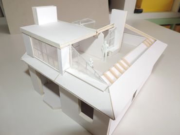 A white architectural model of a modern house with stairs and balcony.