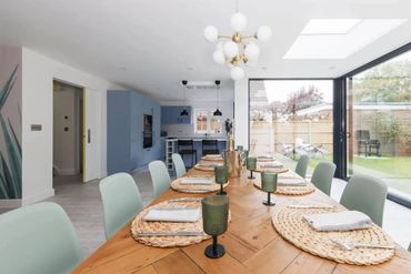 Modern dining room with a long wooden table and large glass windows.